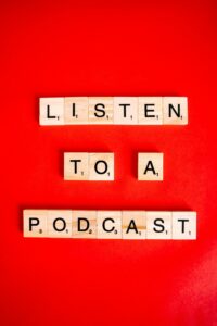 Wooden Scrabble tiles on red background spelling 'Listen to a Podcast'.