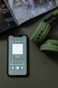 Modern smartphone and green headphones next to a magazine, showcasing technology and lifestyle.